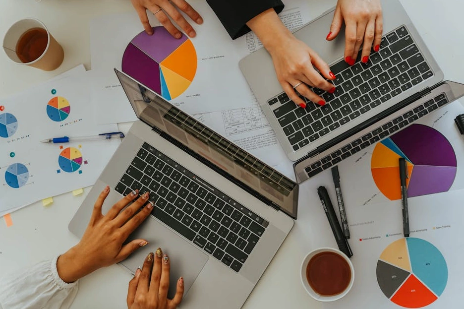 Tým analytiků spolupracuje u stolu s notebooky a grafy